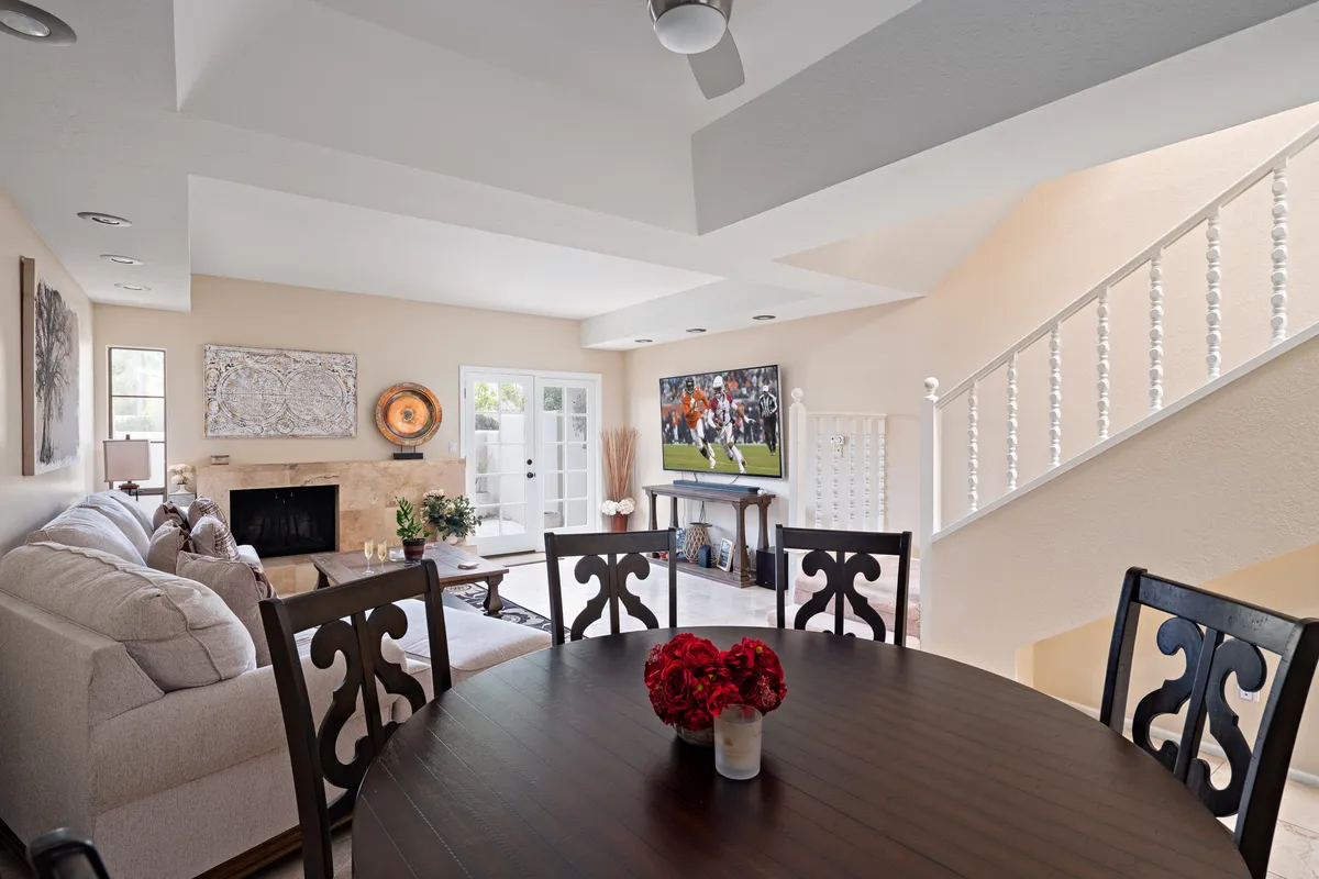 A spacious open-concept living and dining area featuring a plush sofa, cozy fireplace, large dining table, and a wall-mounted 65” 4K Smart TV. The room is styled for both comfort and elegance, with soft lighting and tasteful décor perfect for relaxation or social gatherings.